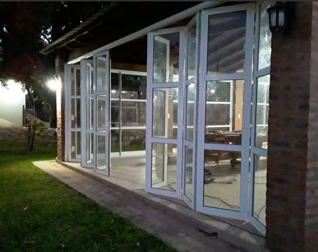 Cerramiento de galería con puertas plegables de vidrio, de noche
