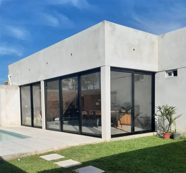 Casa moderna con ventanales corredizos de aluminio negro mate